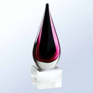 A teardrop shaped piece of glass with shades of burgundy on the outside and black on the inside. It's mounted on a clear cube glass base that's there for personalization.