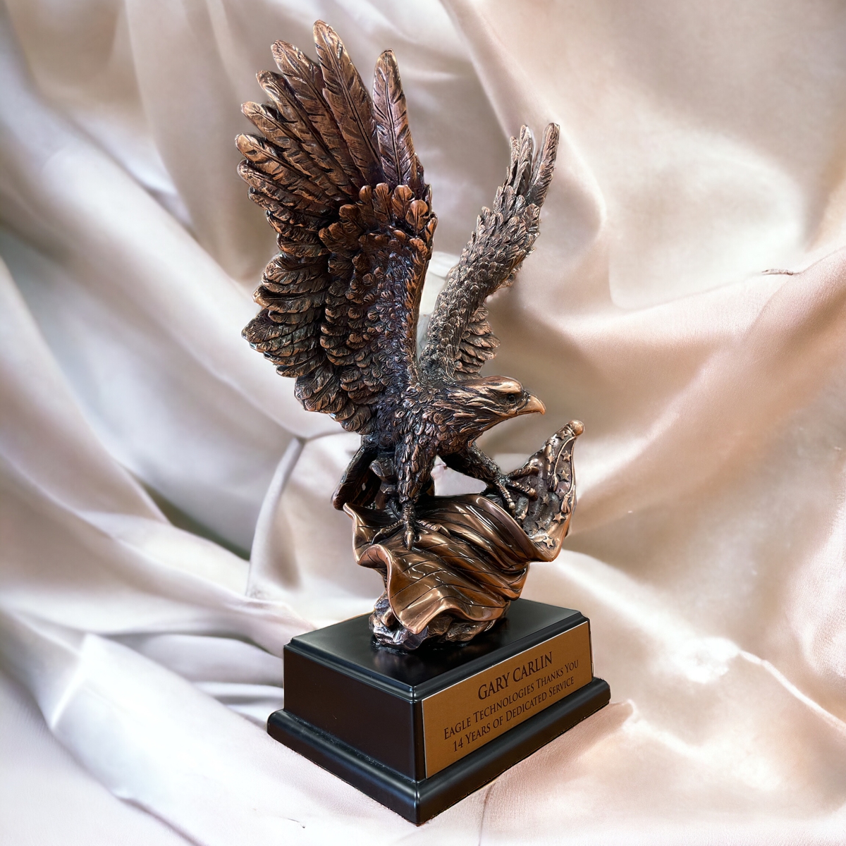 Our Bronze Eagle Statue with an American Flag facing towards the right in front of a satin background.