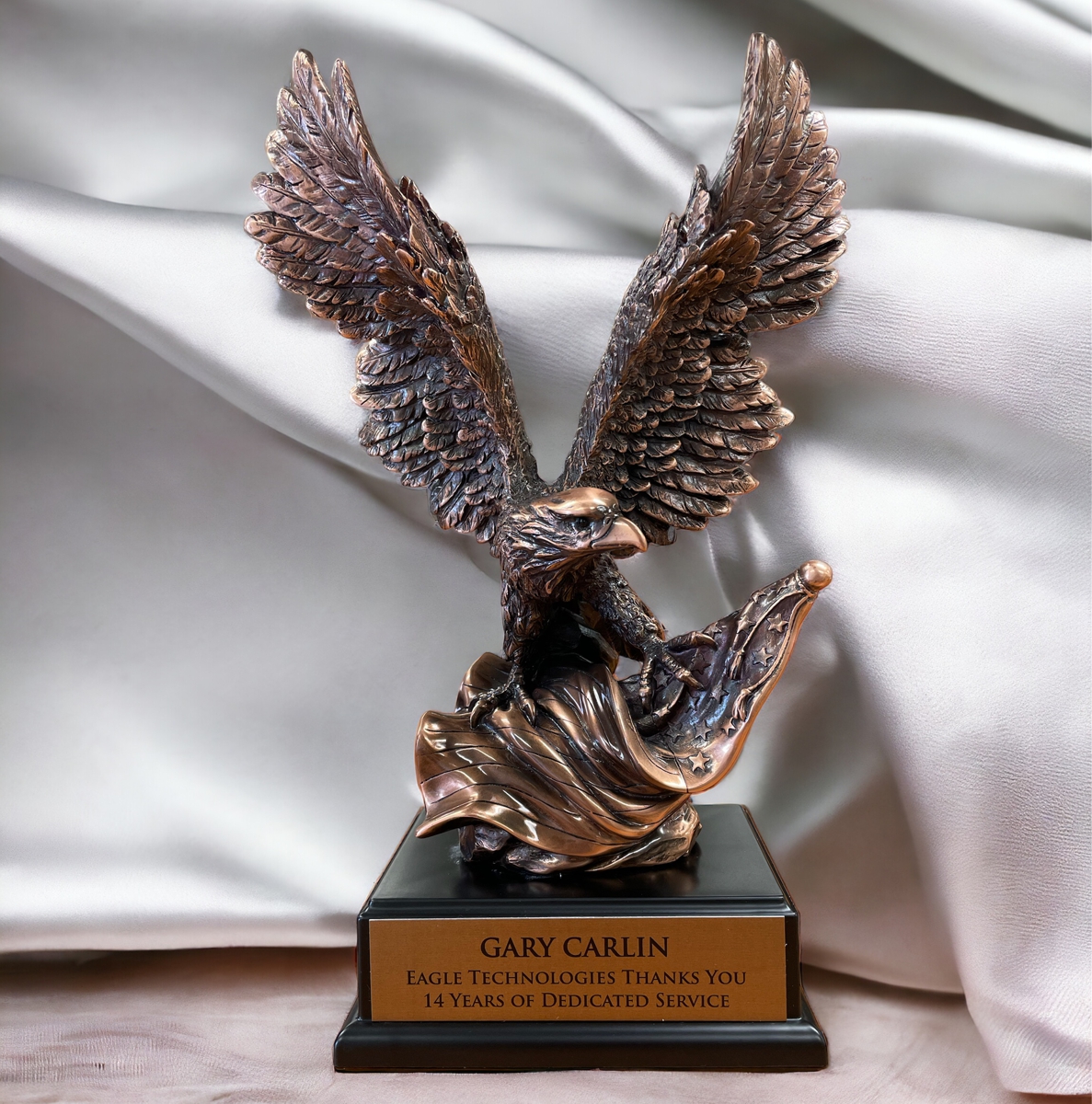 Our Bronze Eagle Statue with an American Flag in front of a satin background.