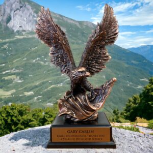 Our Bronze Eagle Statue with an American Flag features a bronze eagle statue with the eagle holding the flag in it's talons. It's mounted on a black base that includes a bronze engraving plate for personalization.