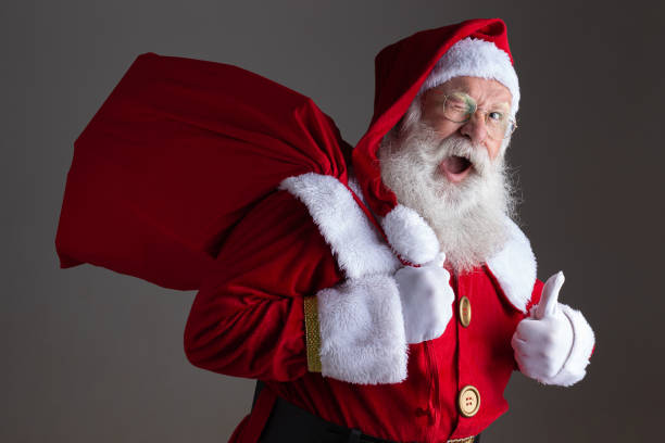 Santa Claus holding his red bag over his shoulder. He's also winking at the camera and is giving a "thumbs up" with his left hand.