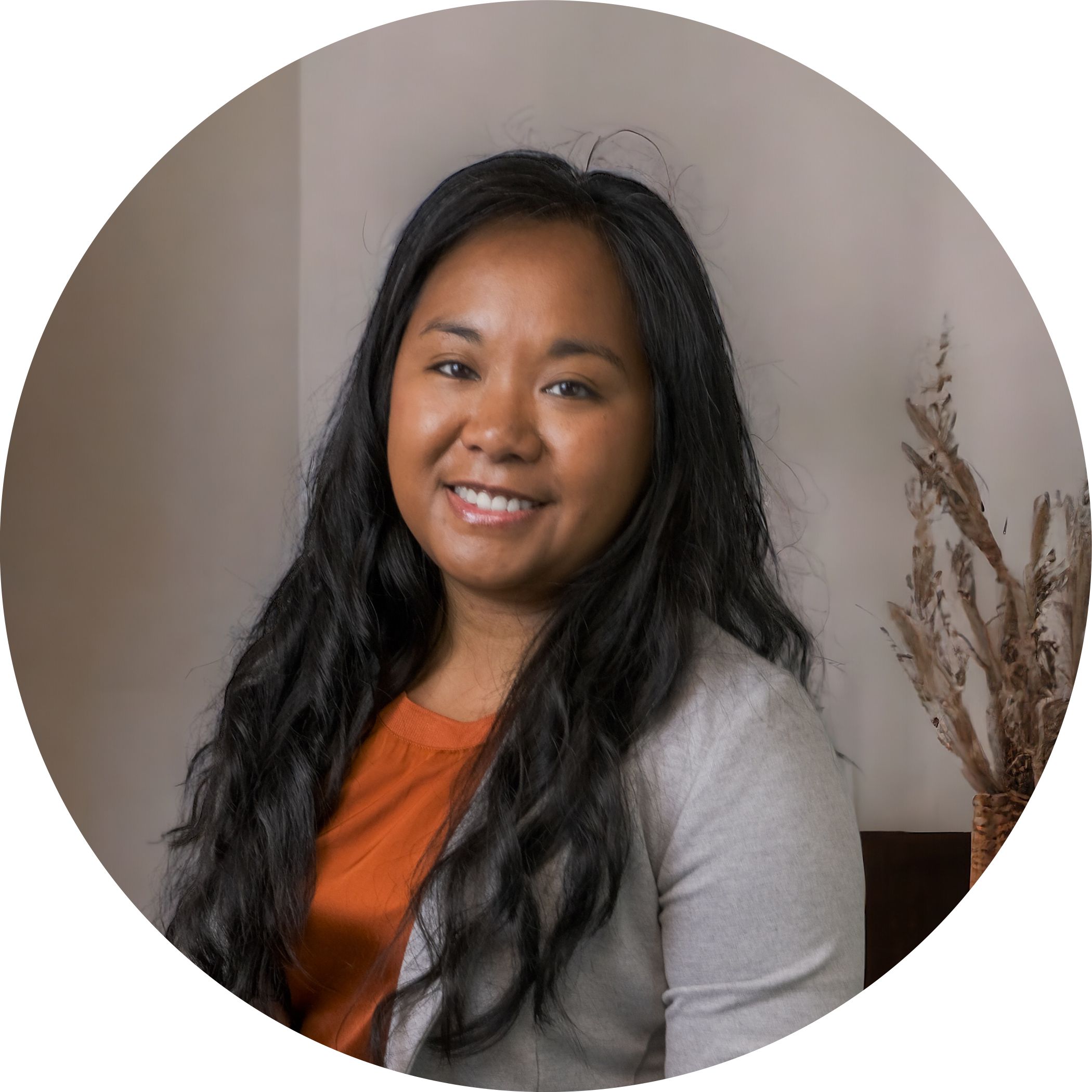 Alyssa Pitchford is an employee for Hit Trophy. Here she is shown in an office setting with her black hair down over her orange blouse & gray top.