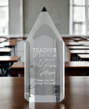 Our Crystal Pencil Award features a thick piece of crystal in the shape of a pencil. It even has a black accent at the top where the lead would be. The front area is for laser engraving personalization for any teacher, education administrator, journalist, author or any other writing themed profession. This CRY1214M crystal pencil stands 7.75" tall & weighs 3.8 lbs. It's sitting on a desk in a classroom with students desks in the background.